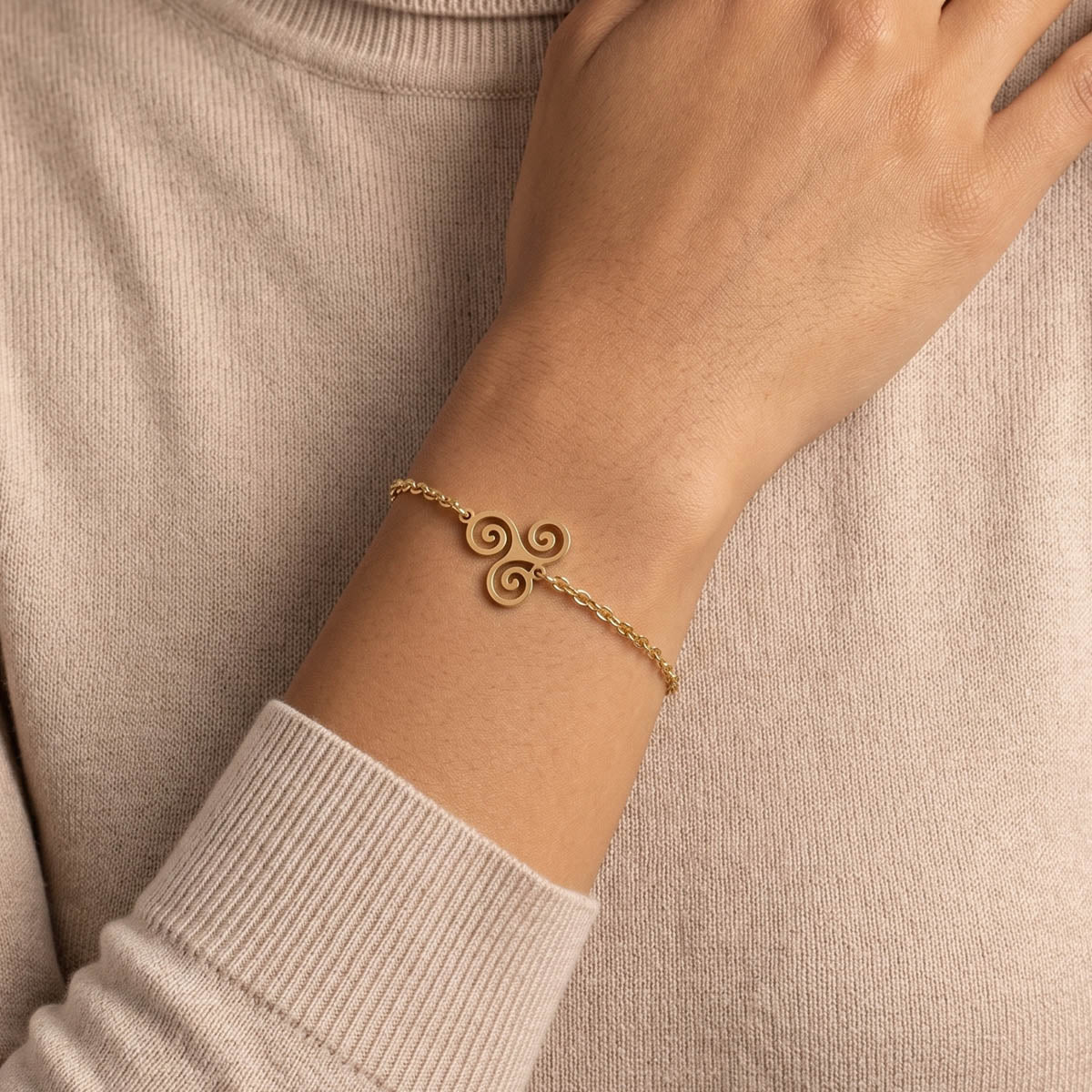 Goldfarbenes Damen Armband mit Keltischem Anhänger am Handgelenk eines Models getragen.