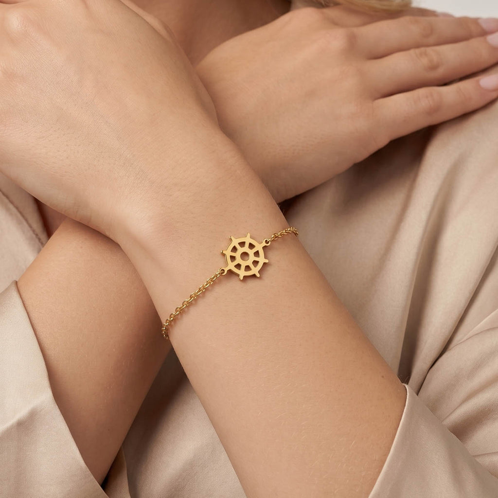 Goldfarbenes Damen Armband mit Steuerrad Anhänger am Handgelenk eines Models getragen.