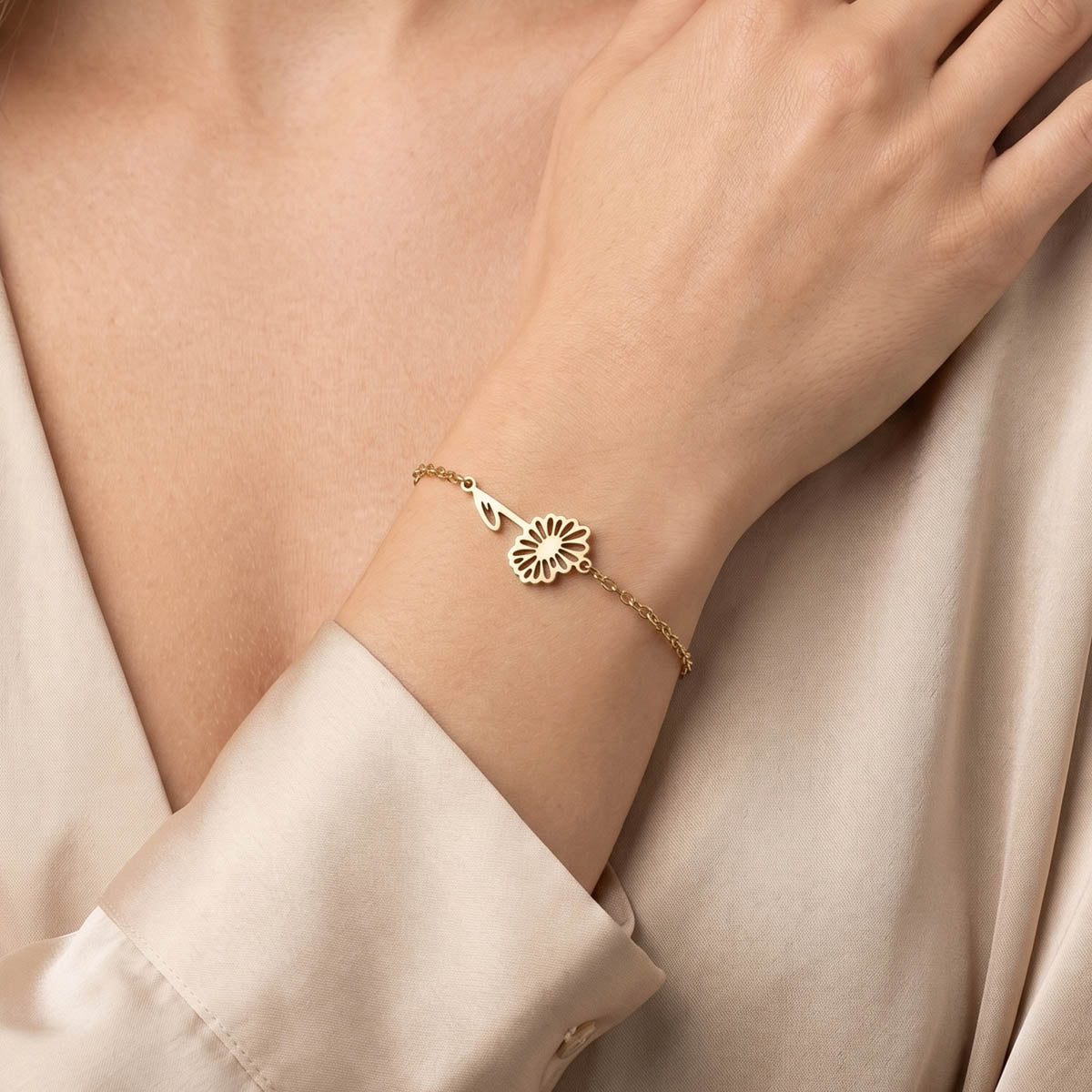 Goldfarbenes Damen Armband mit Blumen Anhänger am Handgelenk eines Models getragen.