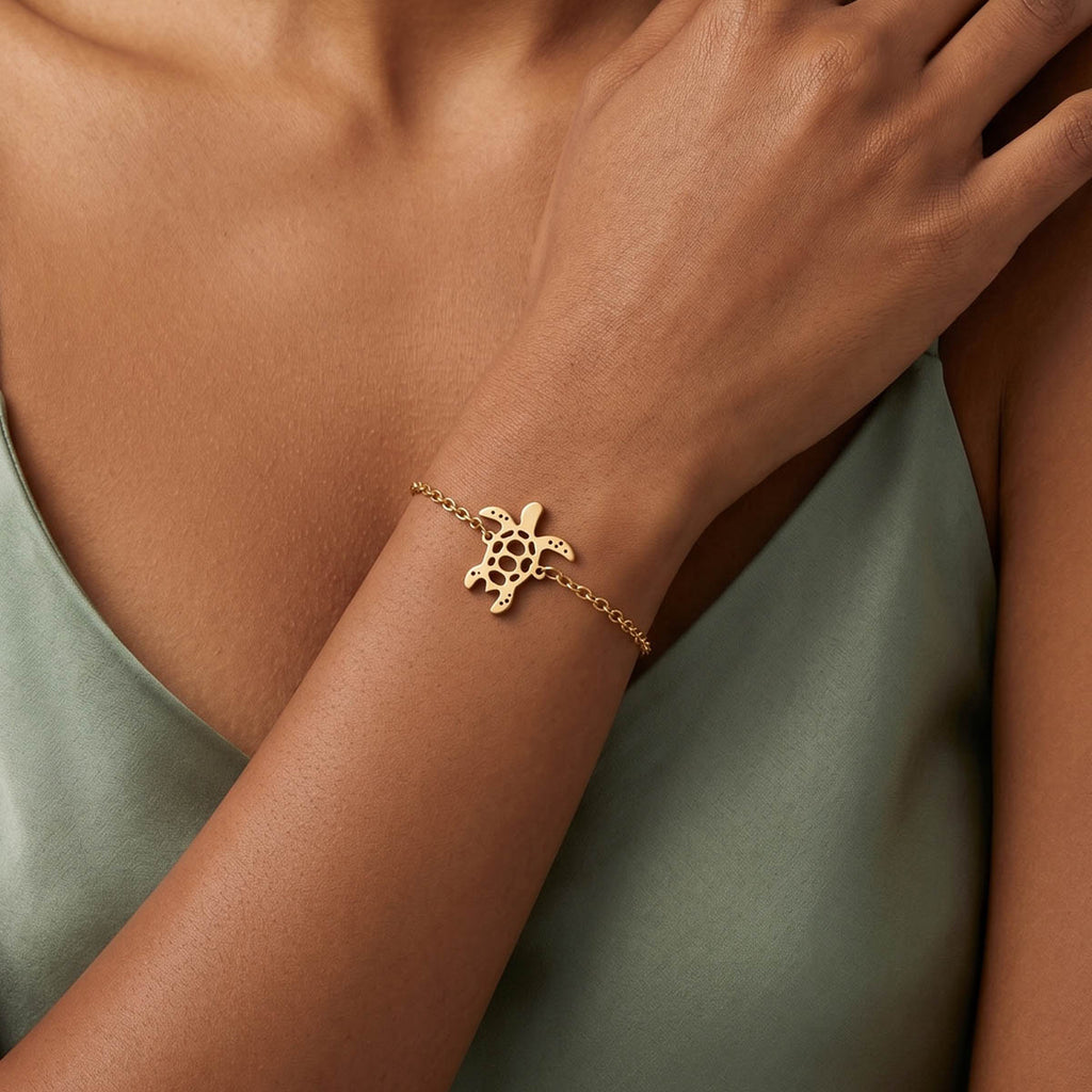 Goldfarbenes Damen Armband mit Schildkröten Anhänger am Handgelenk eines Models getragen.