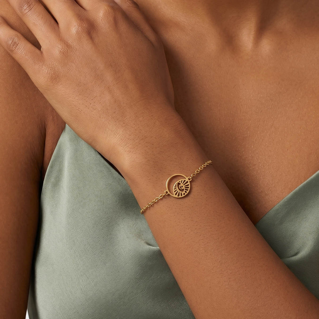 Goldfarbenes Damen Armband mit Augen Motiv Anhänger am Handgelenk eines Models getragen.