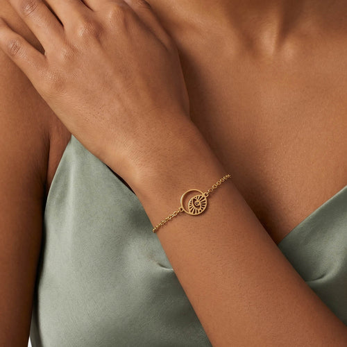 Goldfarbenes Damen Armband mit Augen Motiv Anhänger am Handgelenk eines Models getragen.