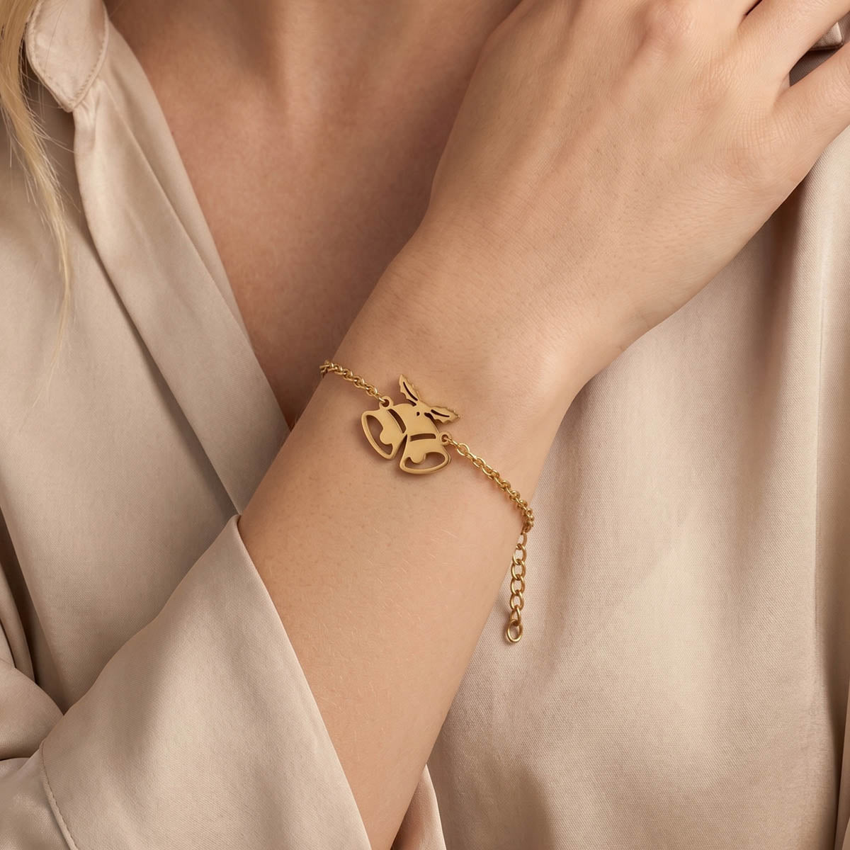 Goldfarbenes Damen Armband mit Weihnachtsglocken Anhänger am Handgelenk eines Models getragen.