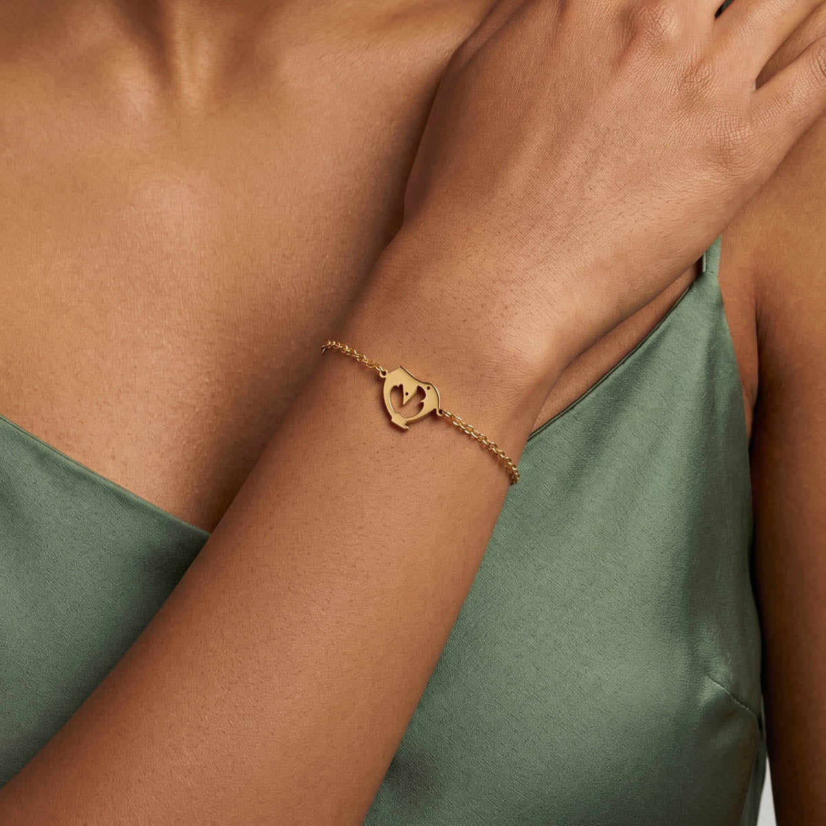 Goldfarbenes Damen Armband mit Delfin Anhänger am Handgelenk eines Models getragen.