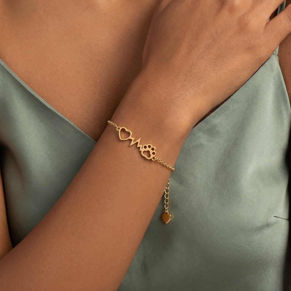 Goldfarbenes Damen Armband mit Herz Pfoten Anhänger am Handgelenk eines Models getragen.