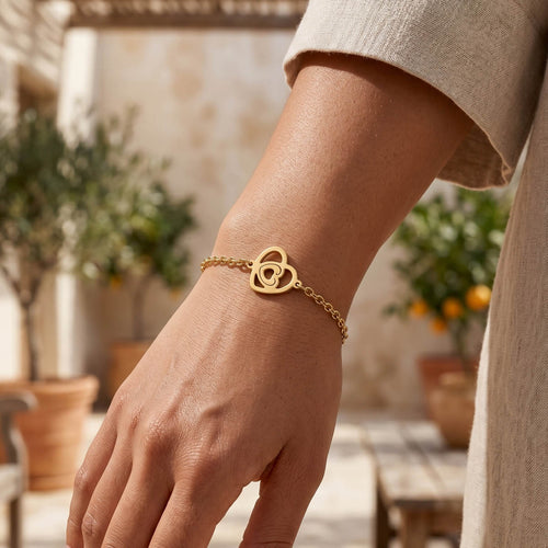 Goldfarbenes Damen Armband mit Herz Anhänger am Handgelenk eines Models getragen.