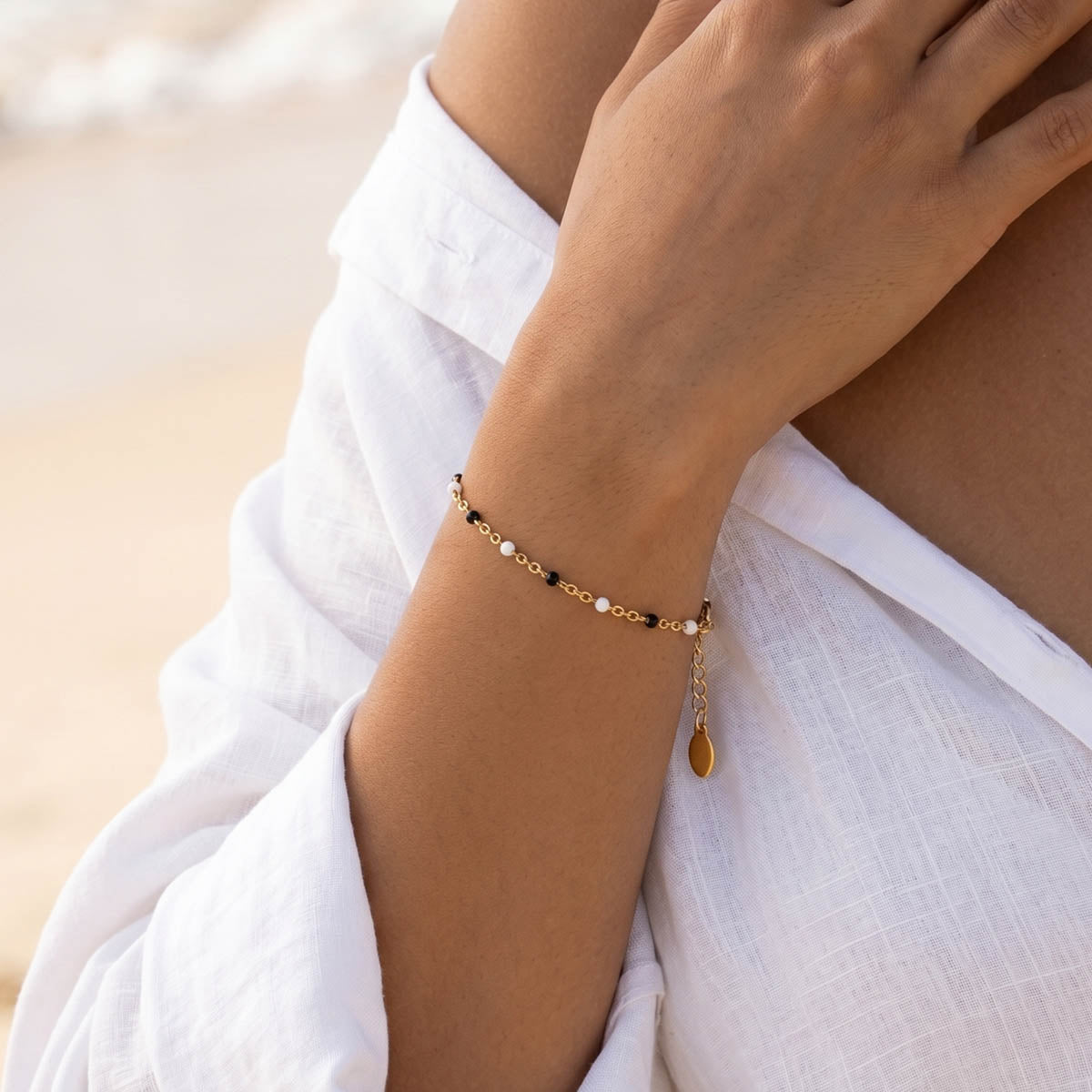 Goldfarbenes Kunstperlen Damen Gliederarmband am Handgelenk eines Models getragen.