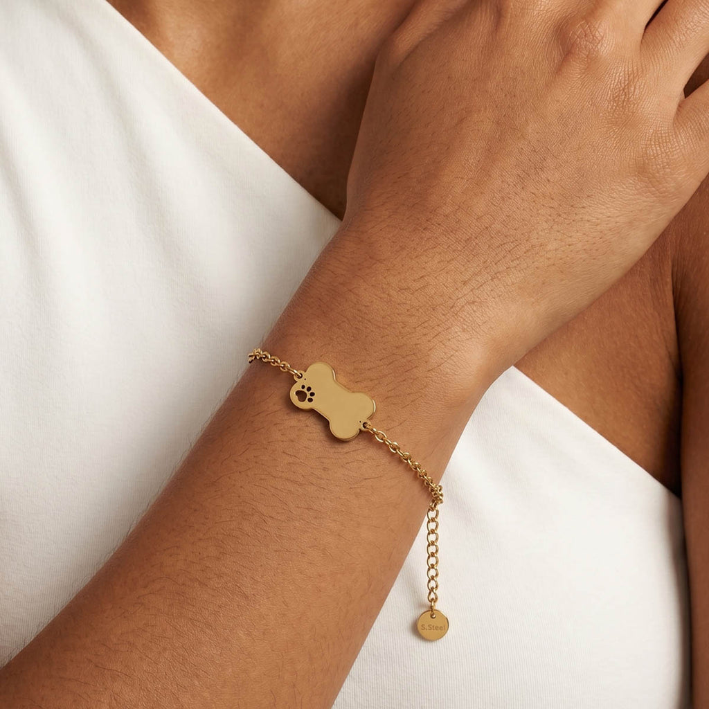 Goldfarbenes Damen Armband mit Knochen Pfoten Anhänger am Handgelenk eines Models getragen.