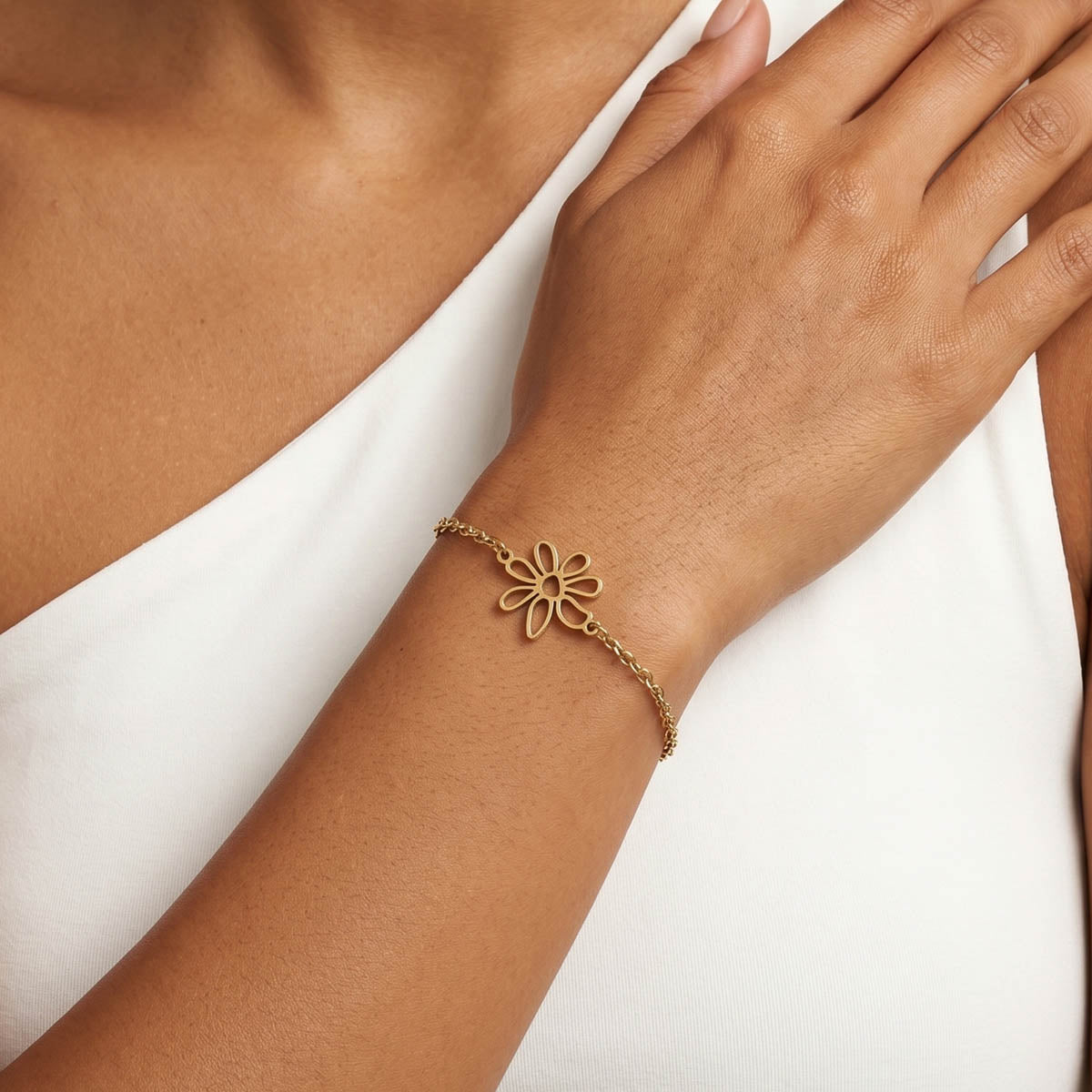 Goldfarbenes Damen Armband mit Blumen Anhänger am Handgelenk eines Models getragen.