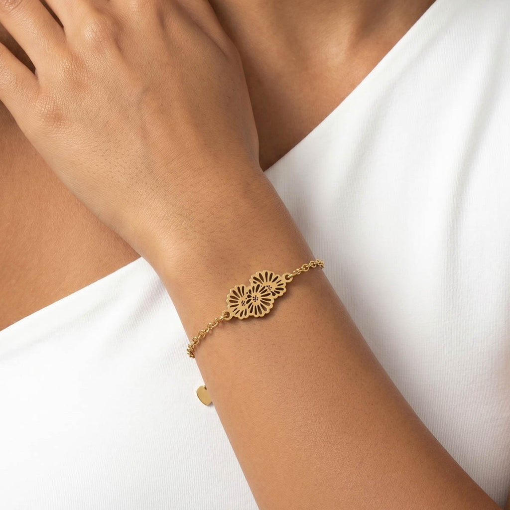 Goldfarbenes Damen Armband mit Blumen Anhänger am Handgelenk eines Models getragen.