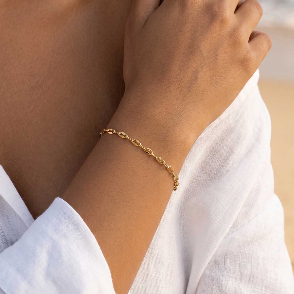 Goldfarbenes Plättchen Armband am Handgelenk eines Models getragen.