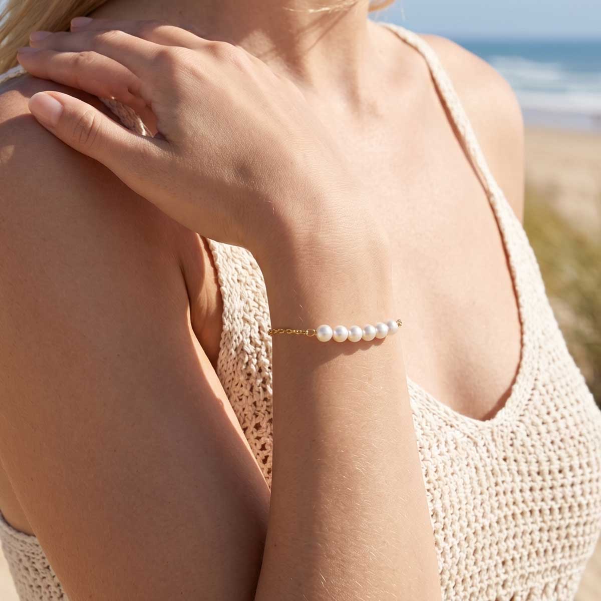 Goldfarbene Damen Perlen Armband Armkette am Handgelenk eines Models getragen.