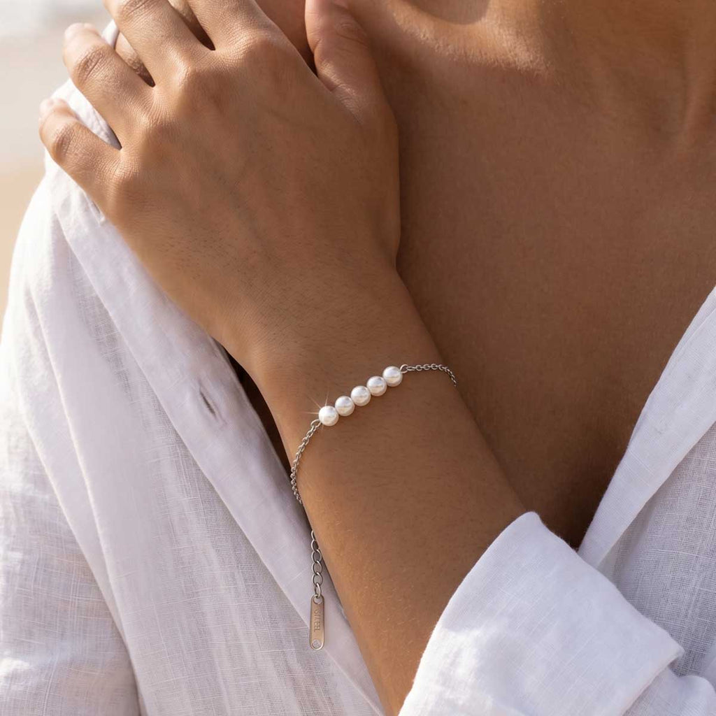 Silberfarbenes Damen Kunstperlen Armband am Handgelenk eines Models getragen.