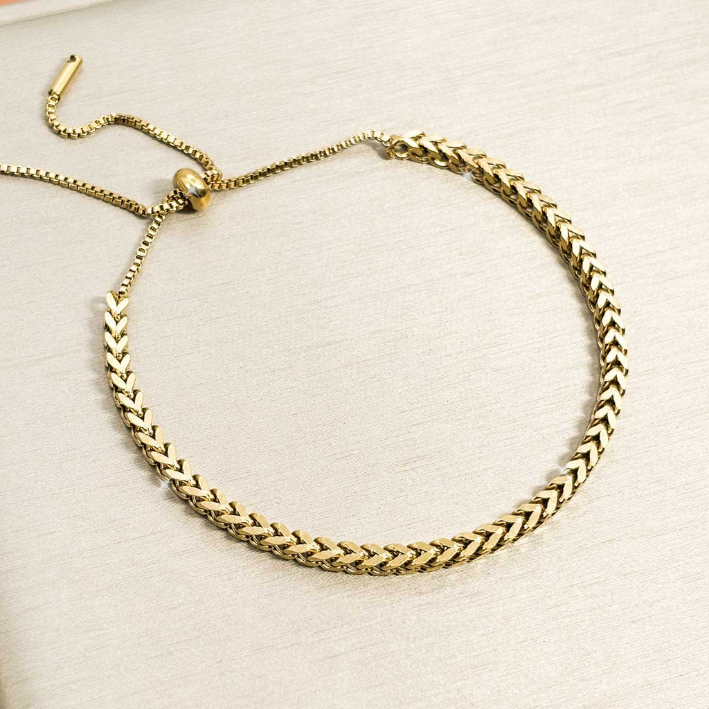 Goldfarbenes Damen-Armband aus Edelstahl im markanten Fischgräten-Design mit einem praktischen, flexiblen Zugverschluss, Produktfoto