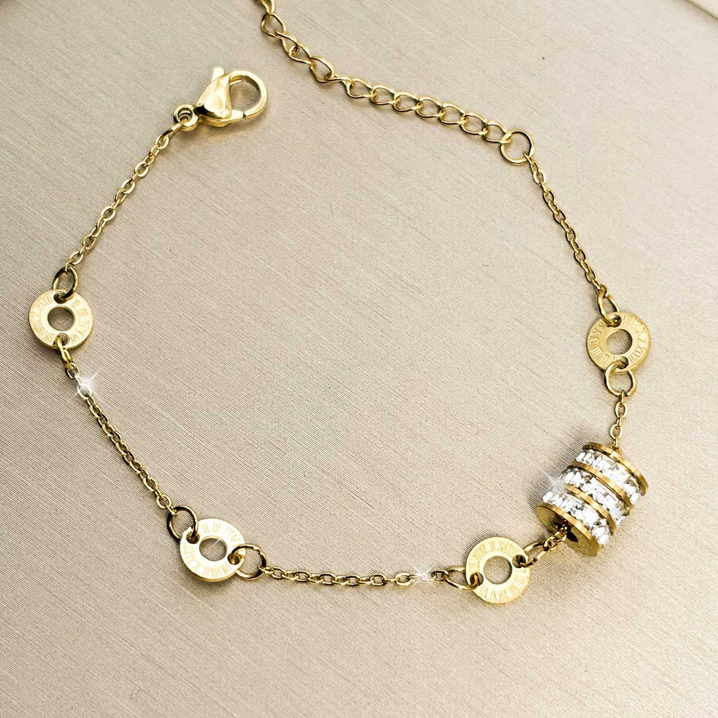 Goldfarbenes Edelstahl-Armband für Damen mit kleinen Logoringen und einem zentralen, voll mit Zirkonia besetzten Zylinder, Produktfoto