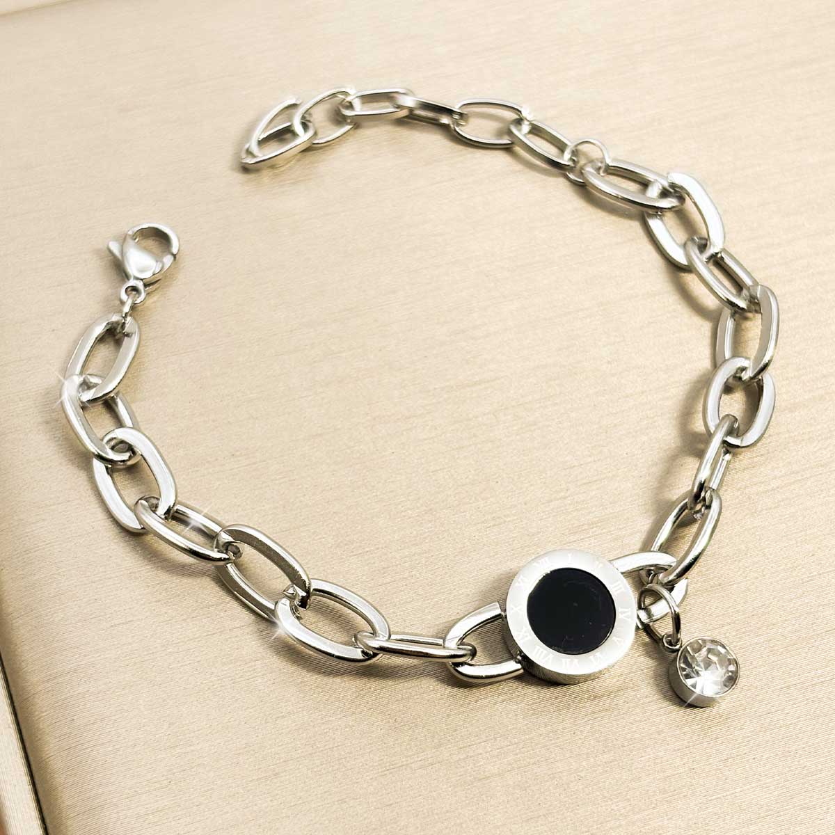 Silberfarbenes Damen-Armband aus Edelstahl mit weiten Kettengliedern, einer runden, schwarzen Einlage und einem hängenden Zirkonia-Stein, Nahaufnahme.