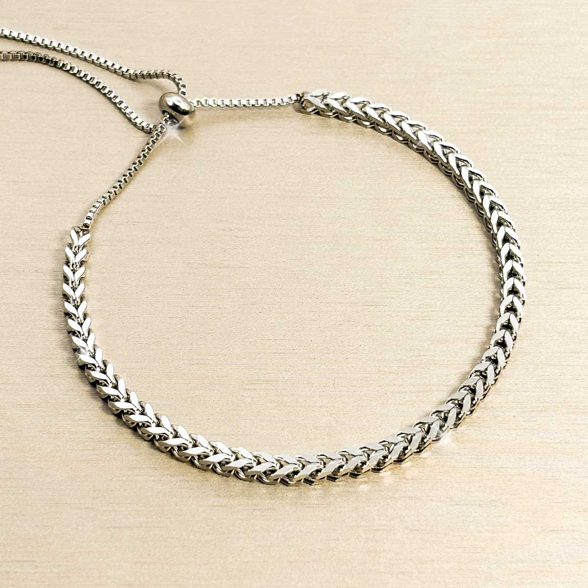 Silberfarbenes Edelstahl-Armband für Damen im markanten Fischgräten-Design mit einem praktischen, flexiblen Zugverschluss, Studioaufnahme.