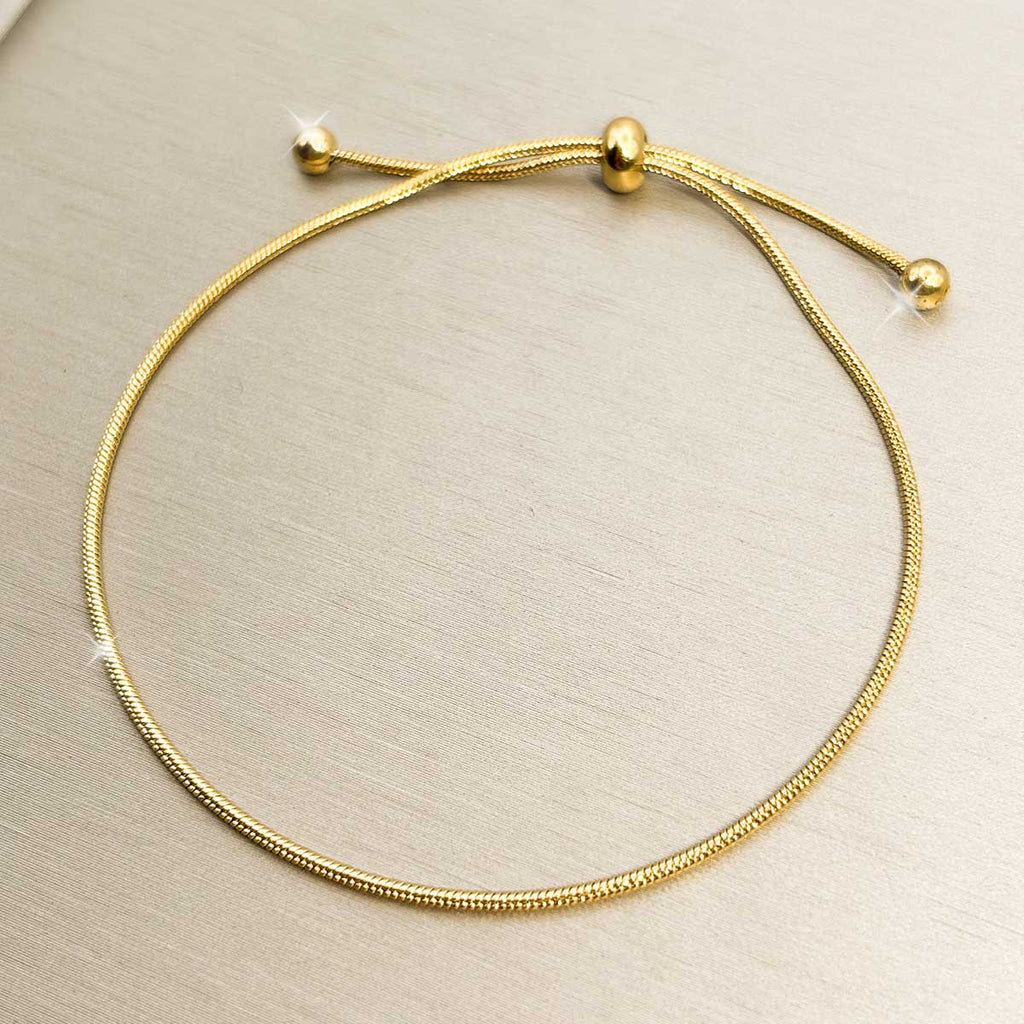 Goldfarbenes Damen-Armband aus Edelstahl im minimalistischen, glatten Schlangenketten-Design mit praktischem Zugverschluss, Produktfoto.