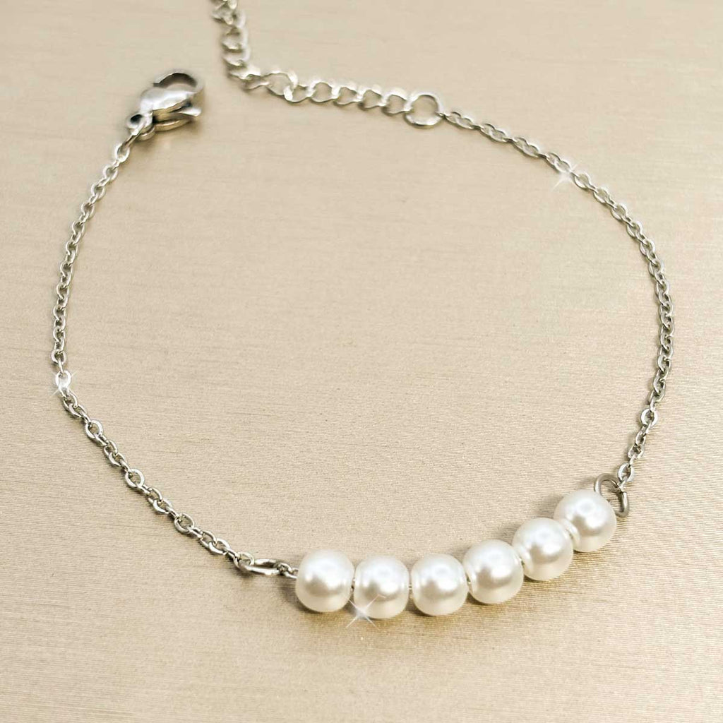 Silberfarbenes Damen-Armband aus Edelstahl mit fünf nebeneinander aufgereihten, weißen Perlen im Zentrum, Produktfoto