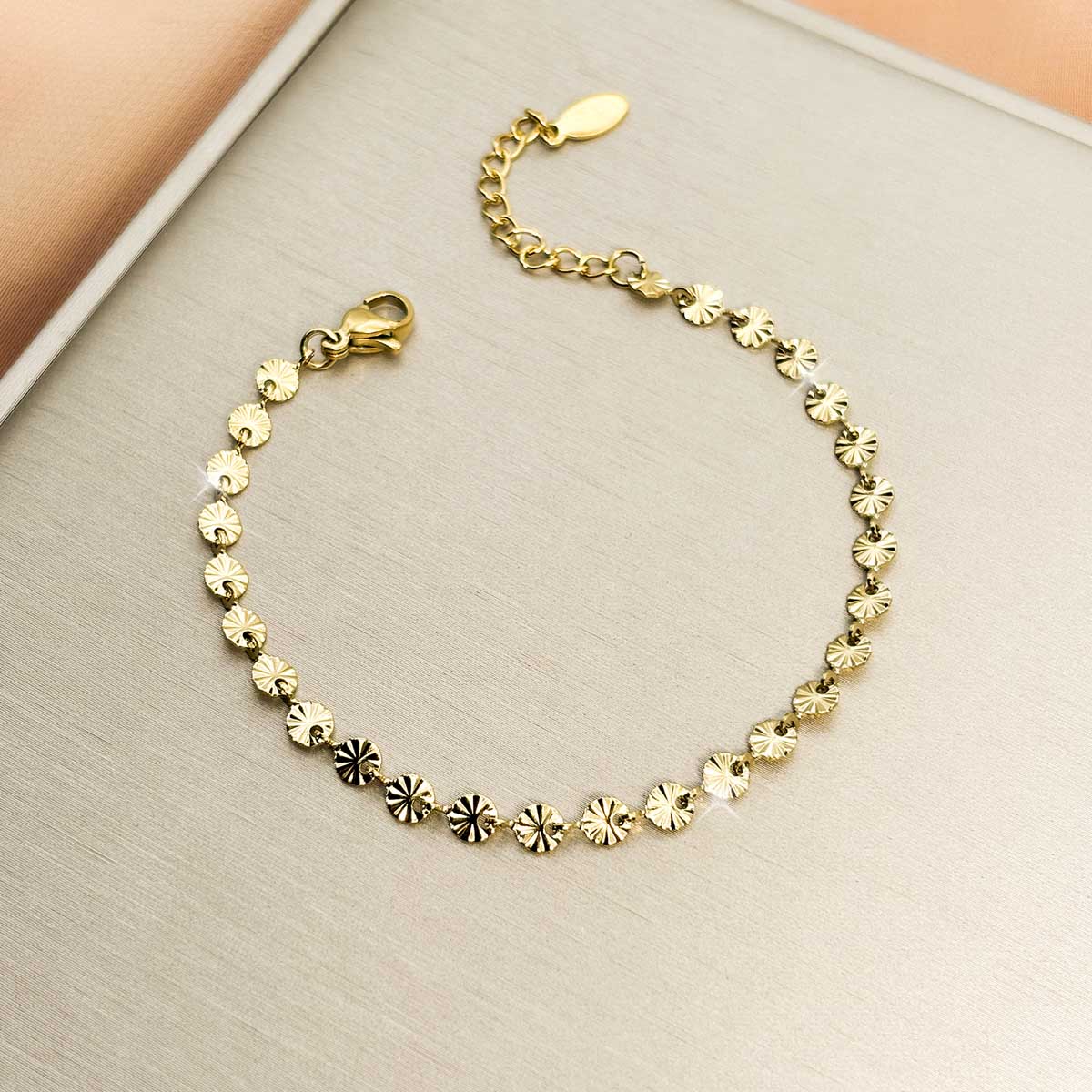 Goldfarbenes Damen-Armband aus Edelstahl, zusammengesetzt aus einer Reihe kleiner, fächerartig strukturierter Plättchen, Nahaufnahme.