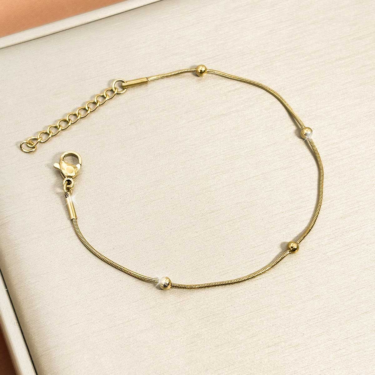 Alt-Text: Goldfarbenes Damen-Armband aus Edelstahl aus einer feinen Schlangenkette mit kleinen integrierten Kugeln, Produktfoto