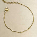 Filigranes goldfarbenes Edelstahl-Armband für Damen, dezent besetzt mit winzigen, gleichmäßig verteilten Kügelchen, Produktbild.