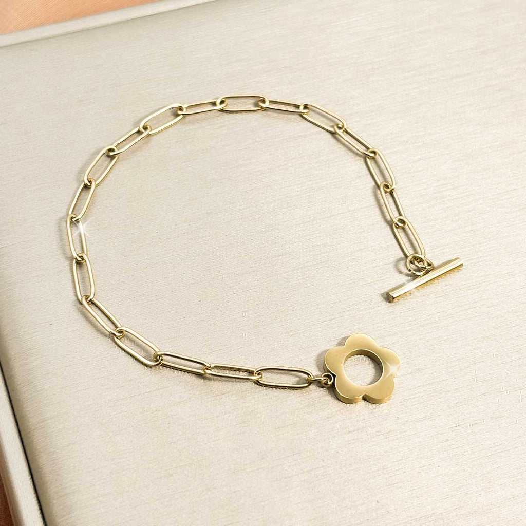 Goldfarbenes Damen-Armband aus Edelstahl mit länglichen Kettengliedern und einem dekorativen Knebelverschluss in Blumen-Form, Nahaufnahme.
