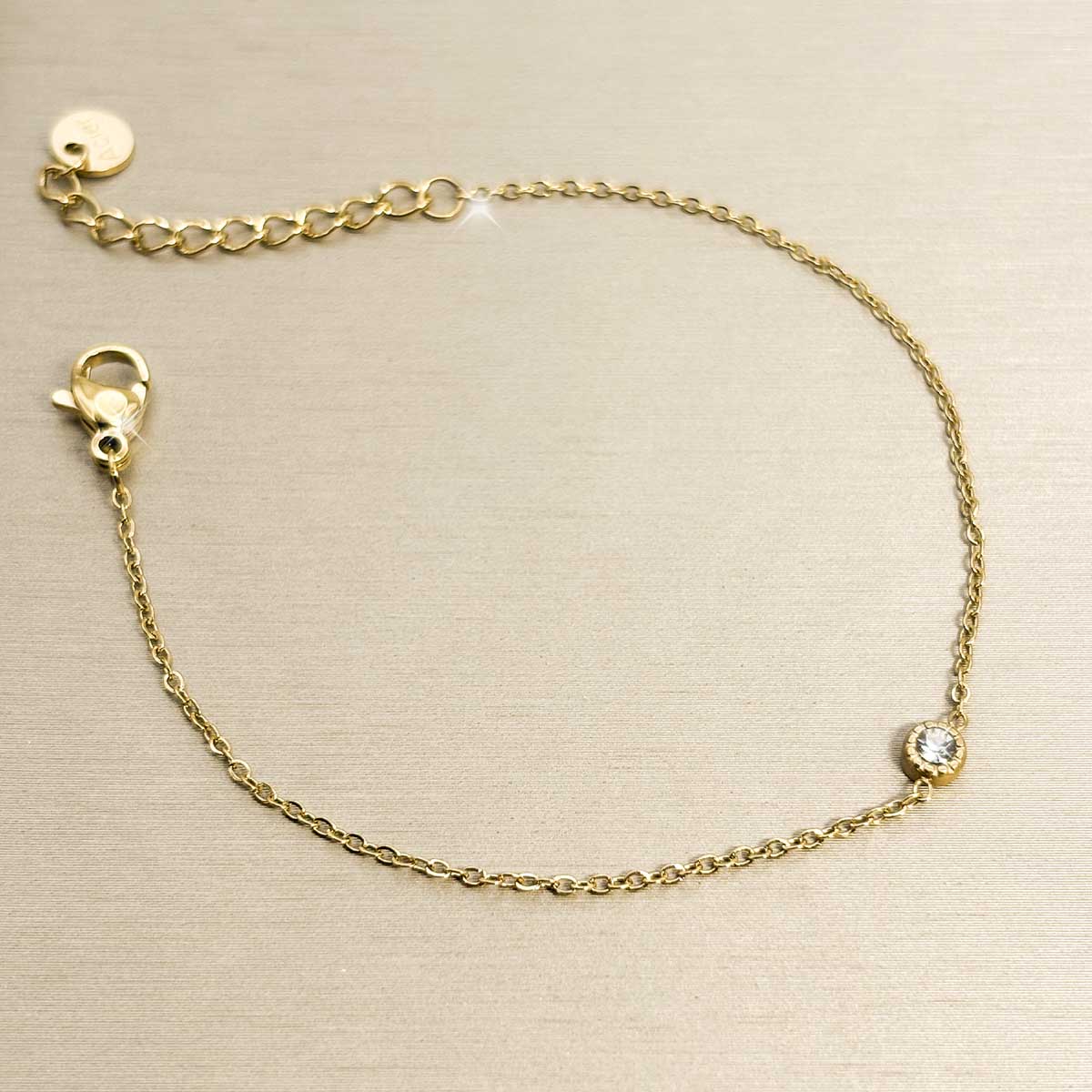 Goldfarbenes Damen-Armband aus Edelstahl aus feiner Kette mit einem winzigen, rund eingefassten Zirkonia-Stein, Produktfoto.