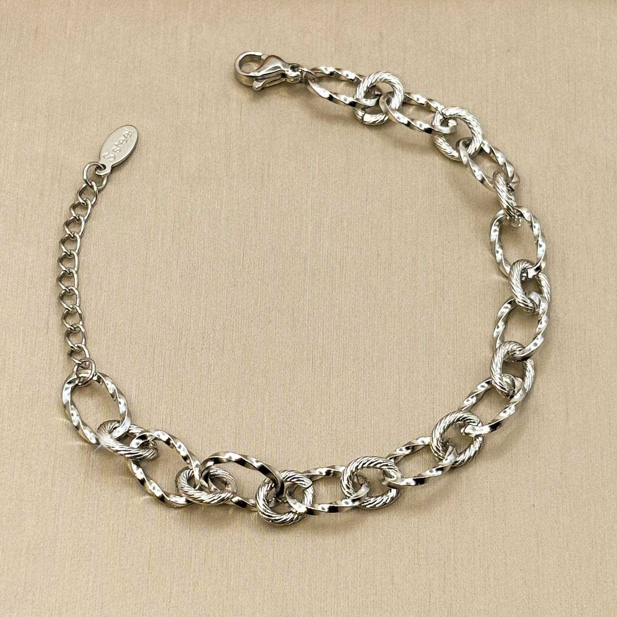Silberfarbenes Edelstahl-Armband für Damen mit gemusterten, ineinander verschlungenen Gliedern, Studioaufnahme.