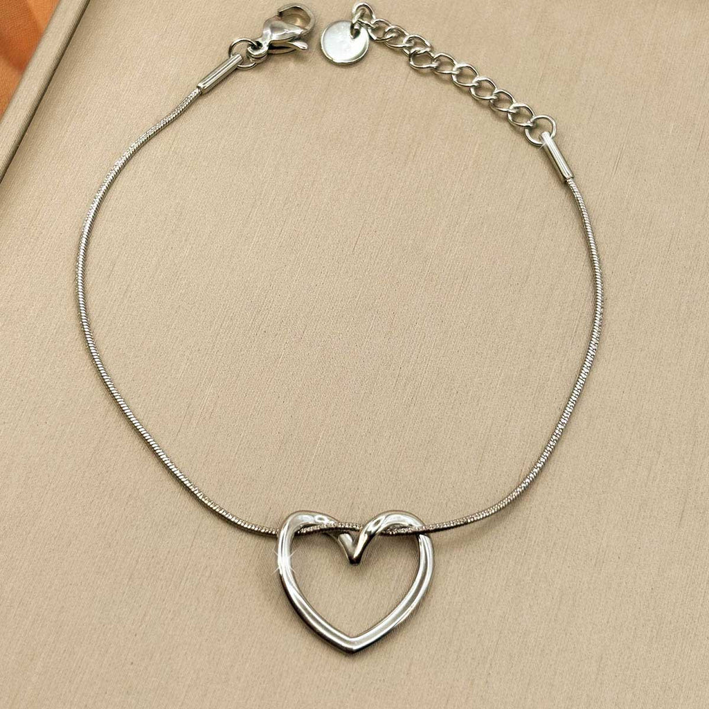 Silberfarbenes Damen-Armband aus Edelstahl mit einem elegant geschwungenen Herz-Anhänger, Nahaufnahme.