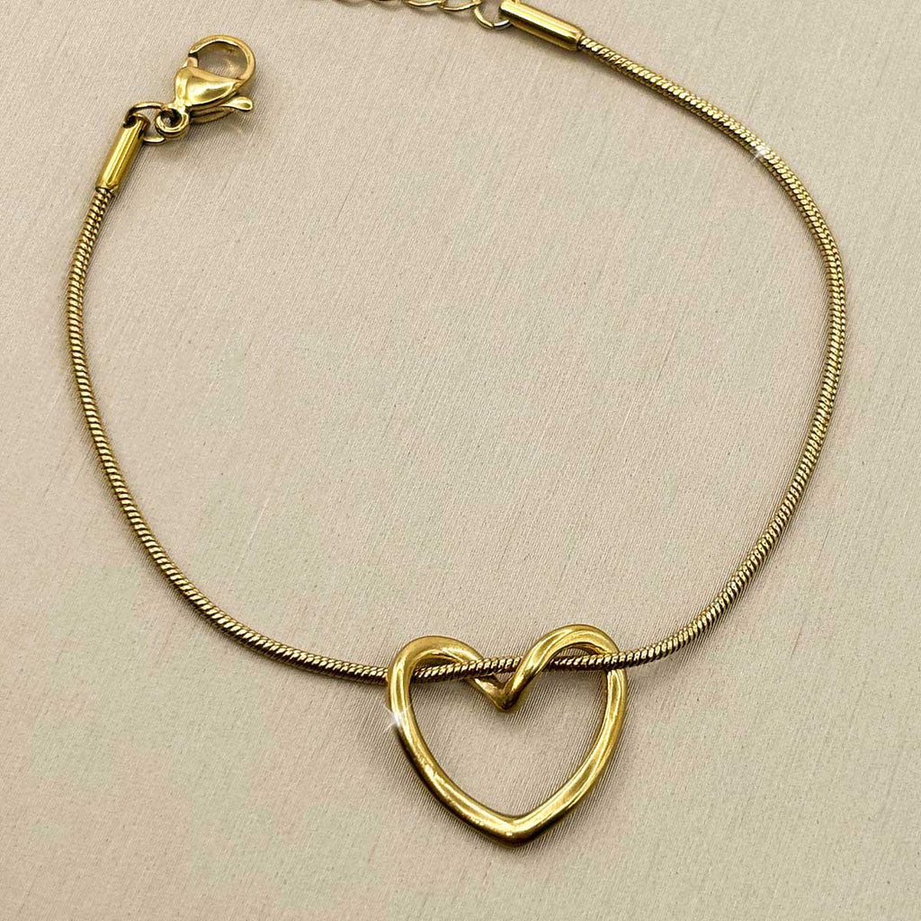 Goldfarbenes Edelstahl-Armband für Damen mit einem mittig integrierten, offenen Herz-Element, Produktbild.