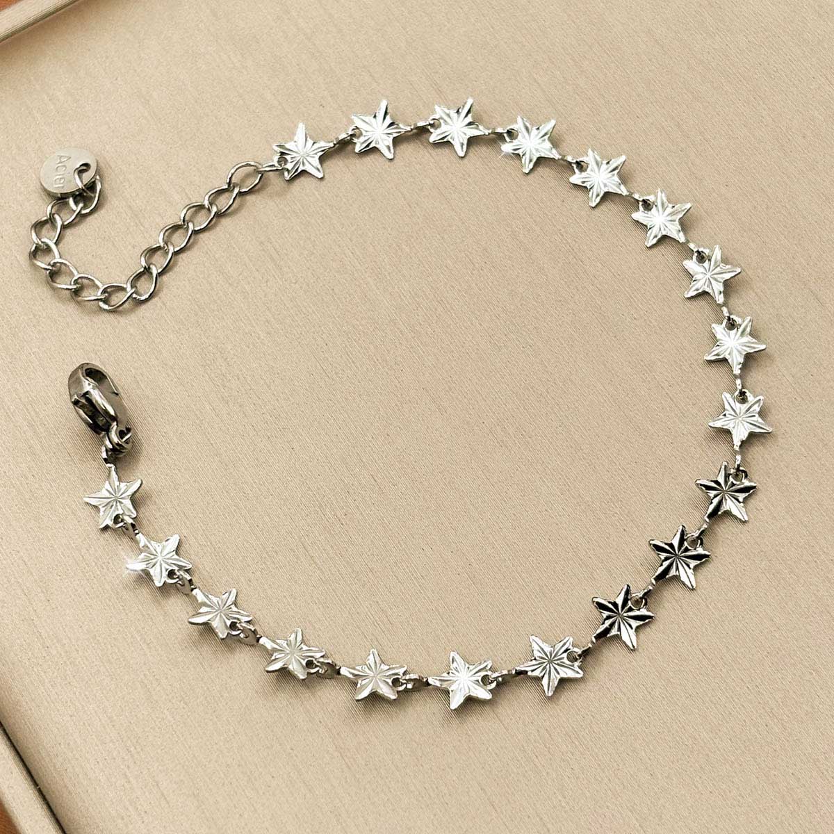 Silberfarbenes Edelstahl-Armband für Damen, bestehend aus einer Kette kleiner, funkelnder Sterne, Studioaufnahme.