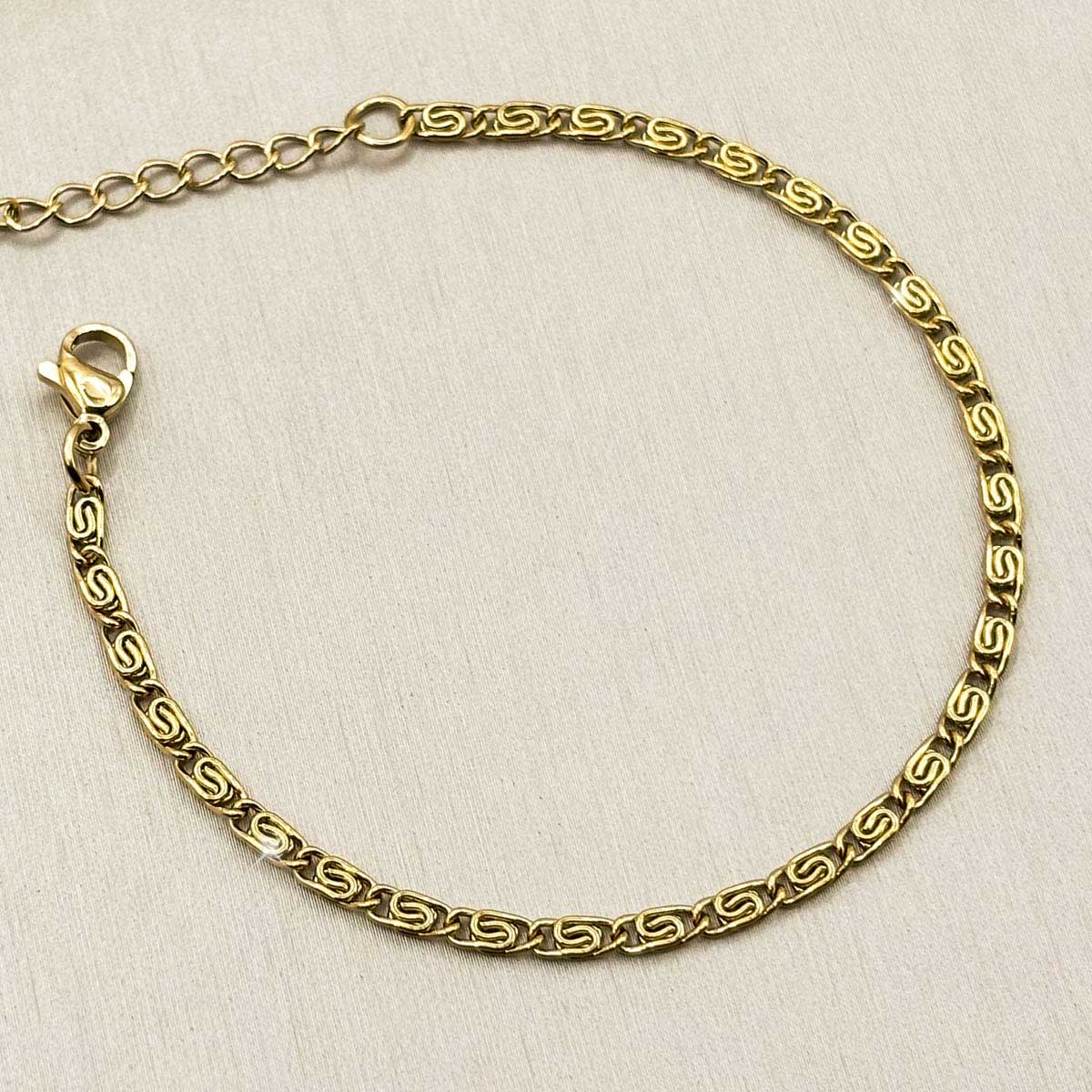 Goldfarbenes Damen-Armband aus Edelstahl mit flach strukturierten, gemusterten Kettengliedern, Detail-Aufnahme.