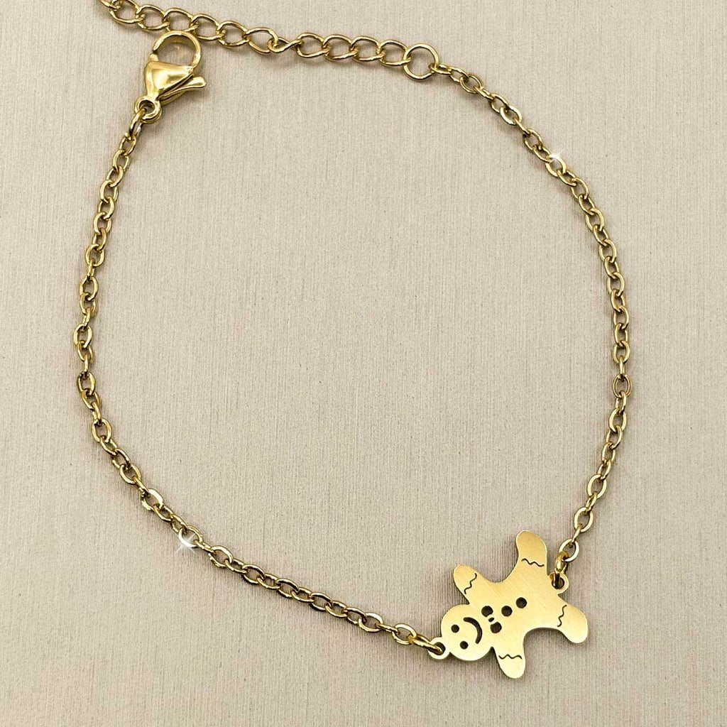 Goldfarbenes Edelstahl-Armband für Damen mit einem kleinen, niedlichen Lebkuchenmann-Element, Studioaufnahme.