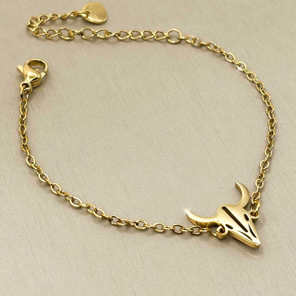Goldfarbenes Damen-Armband aus Edelstahl mit einem markanten Stierschädel-Anhänger im Boho-Stil, Detail-Aufnahme.