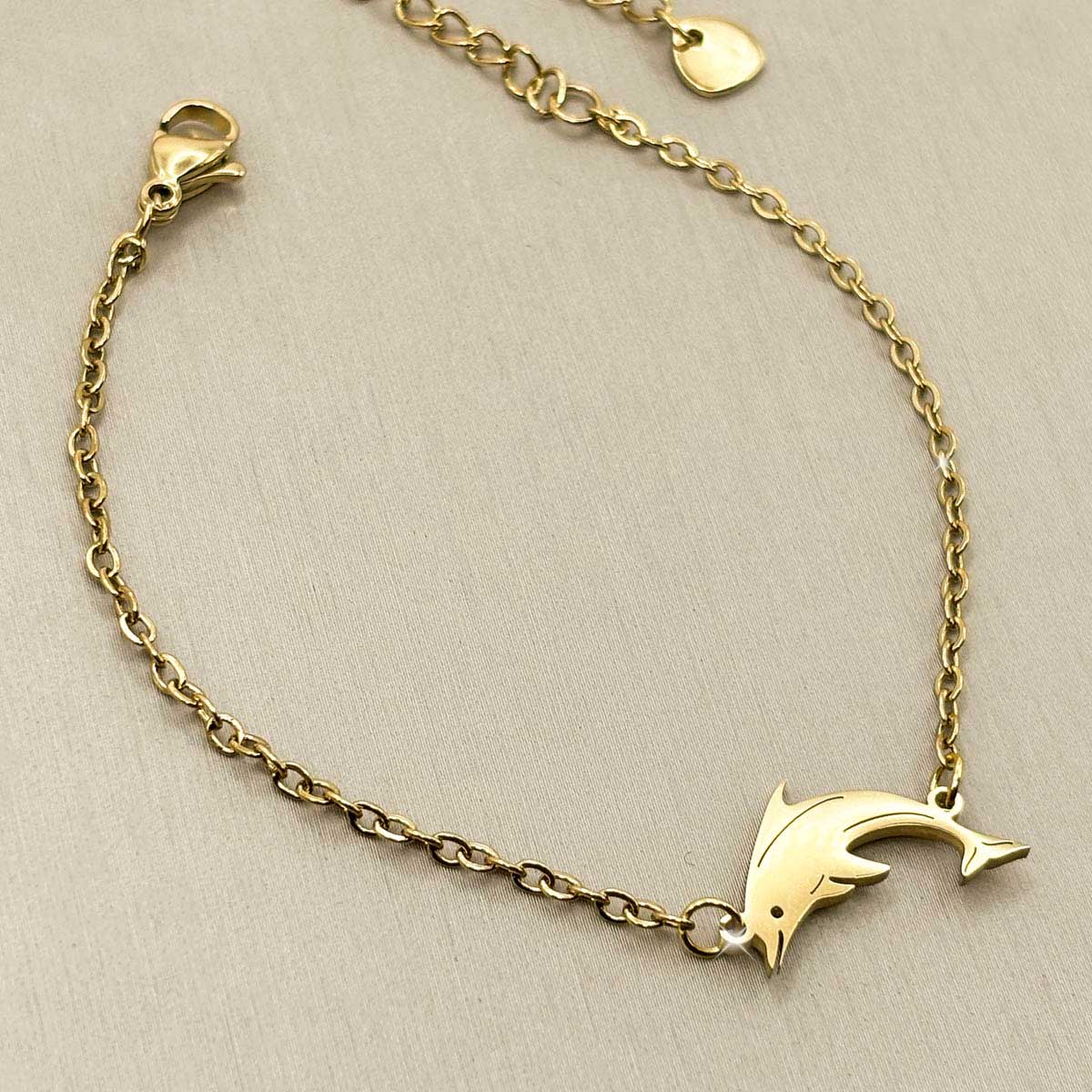 Goldfarbenes Damen-Armband aus Edelstahl mit einem grazilen Delfin-Anhänger, Vorderansicht.