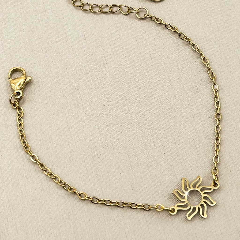 Goldfarbenes Edelstahl-Armband für Damen mit einem kleinen, strahlenden Sonnen-Element, Studioaufnahme.
