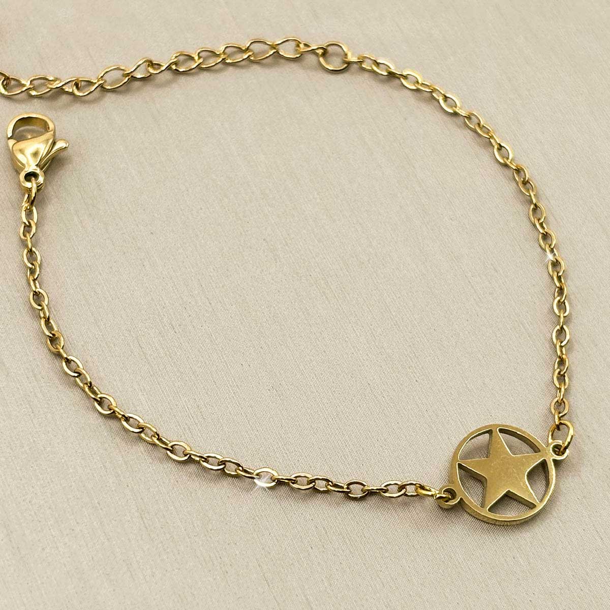 Goldfarbenes Damen-Armband aus Edelstahl mit einem runden Anhänger, der ein ausgestanztes Stern-Motiv zeigt, Vorderansicht.