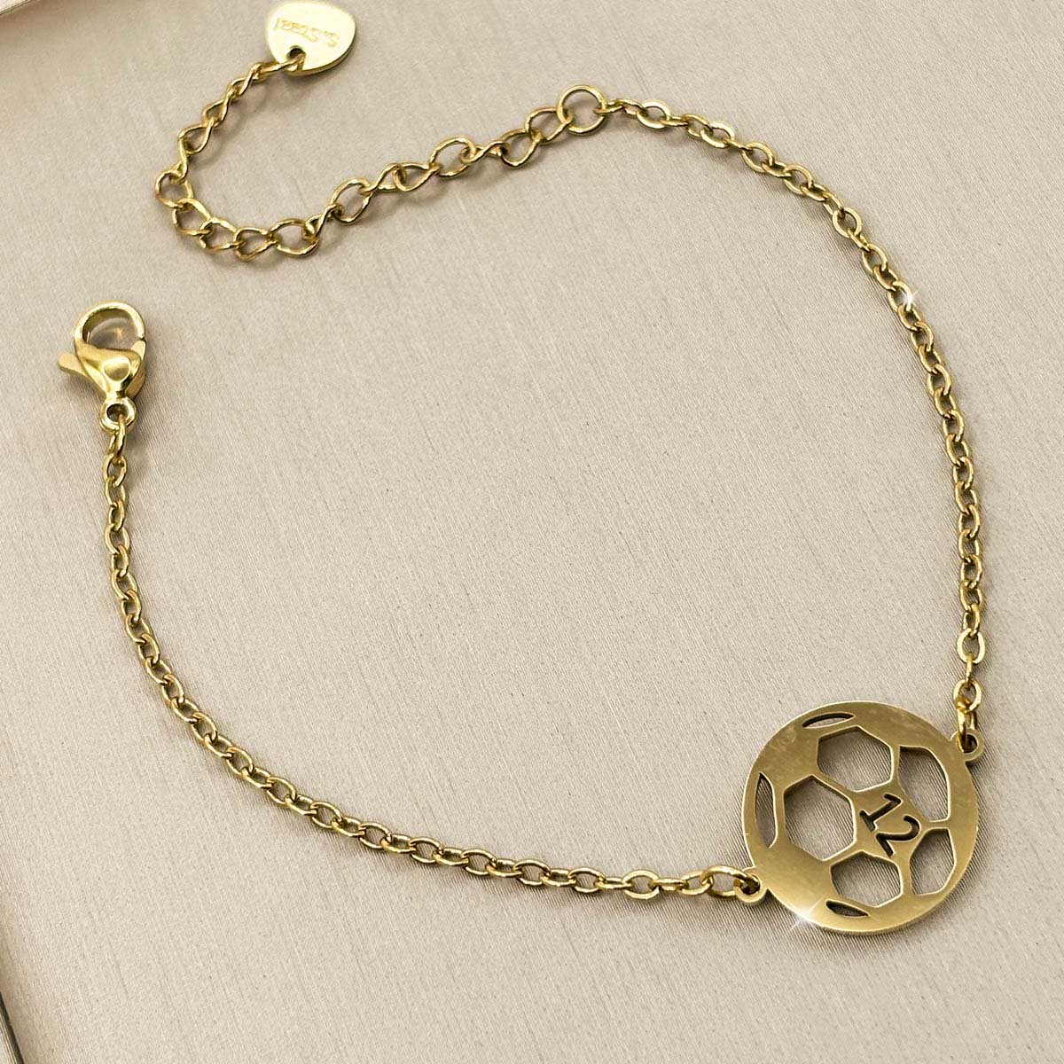 Goldfarbenes Damen-Armband aus Edelstahl mit einem runden Fußball-Anhänger und der Nummer 12, Detail-Aufnahme.