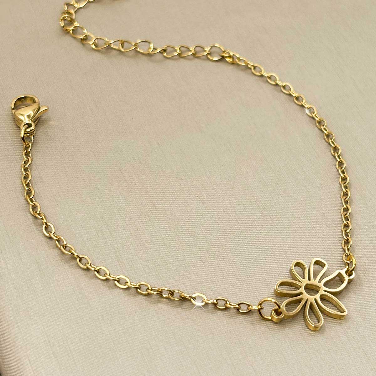 Goldfarbenes Damen-Armband aus Edelstahl mit einer schlichten, ausgestanzten Blüte als Zwischenelement, Produktfoto.
