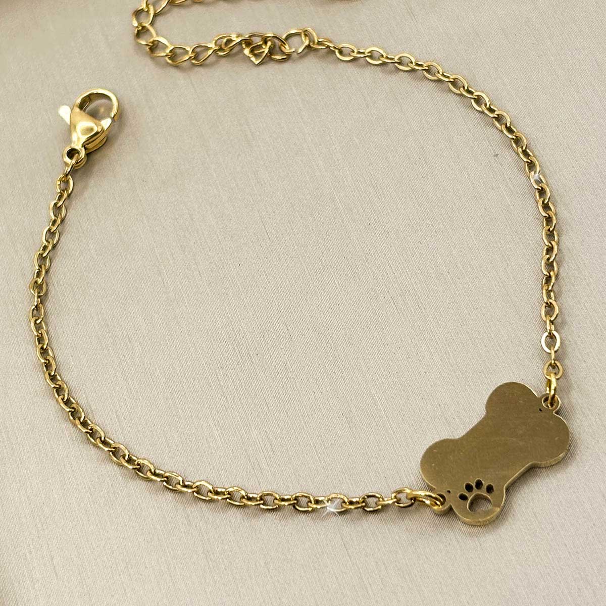 Goldfarbenes Damen-Armband aus Edelstahl mit einem flachen Hundeknochen-Anhänger und kleiner Pfote, Produktfoto