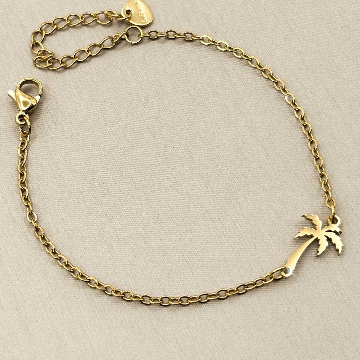 Goldfarbenes Edelstahl-Armband für Damen mit einer filigranen, elegant geschwungenen Palme, Studioaufnahme.