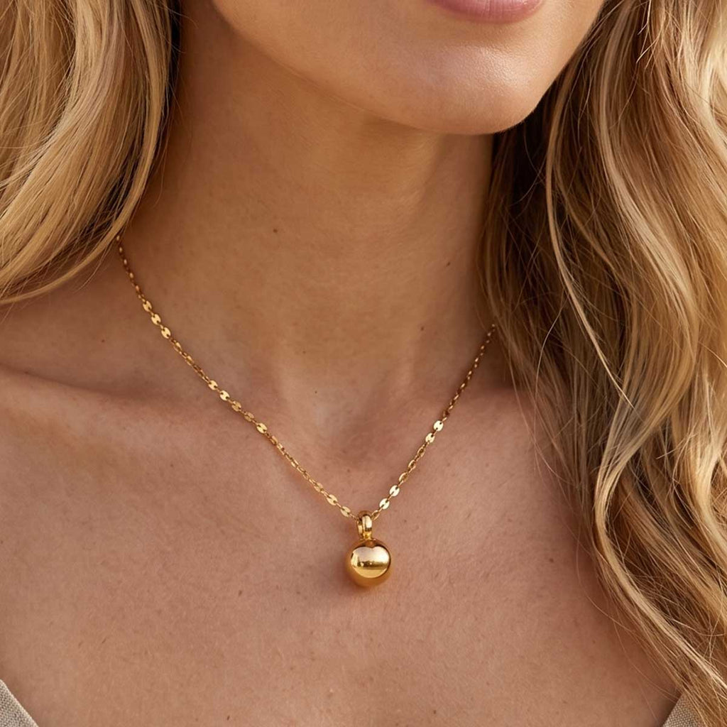 Goldfarbene Damen Halskette mit Kugel Anhänger am Hals eines Models getragen.