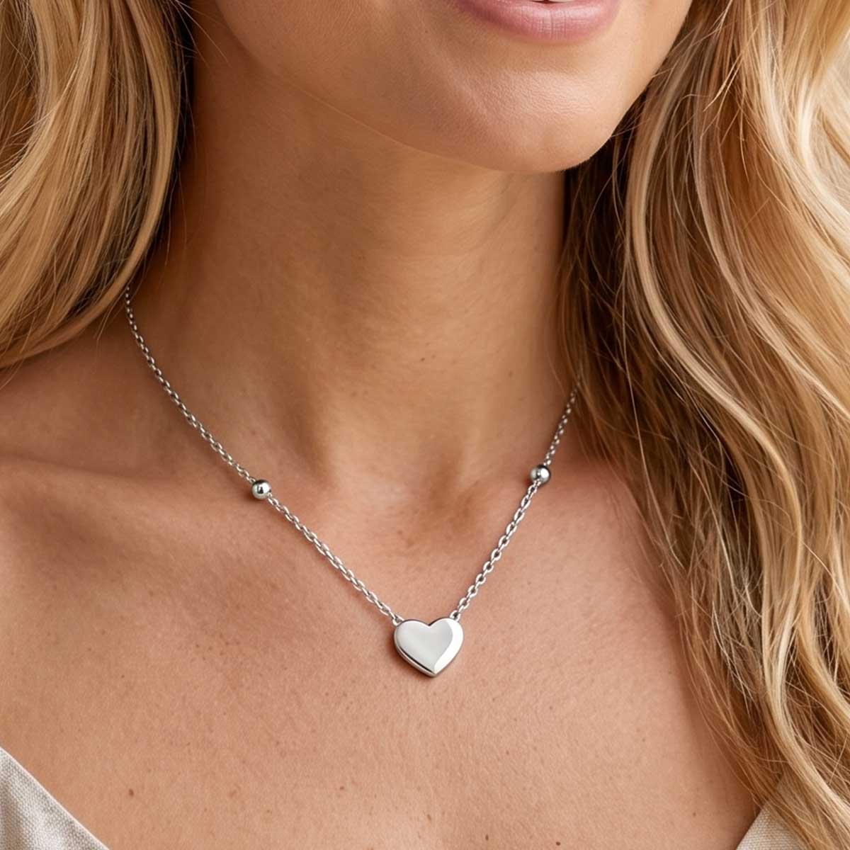 Silberfarbene Damen Halskette mit Herz Anhänger am Hals eines Models getragen.