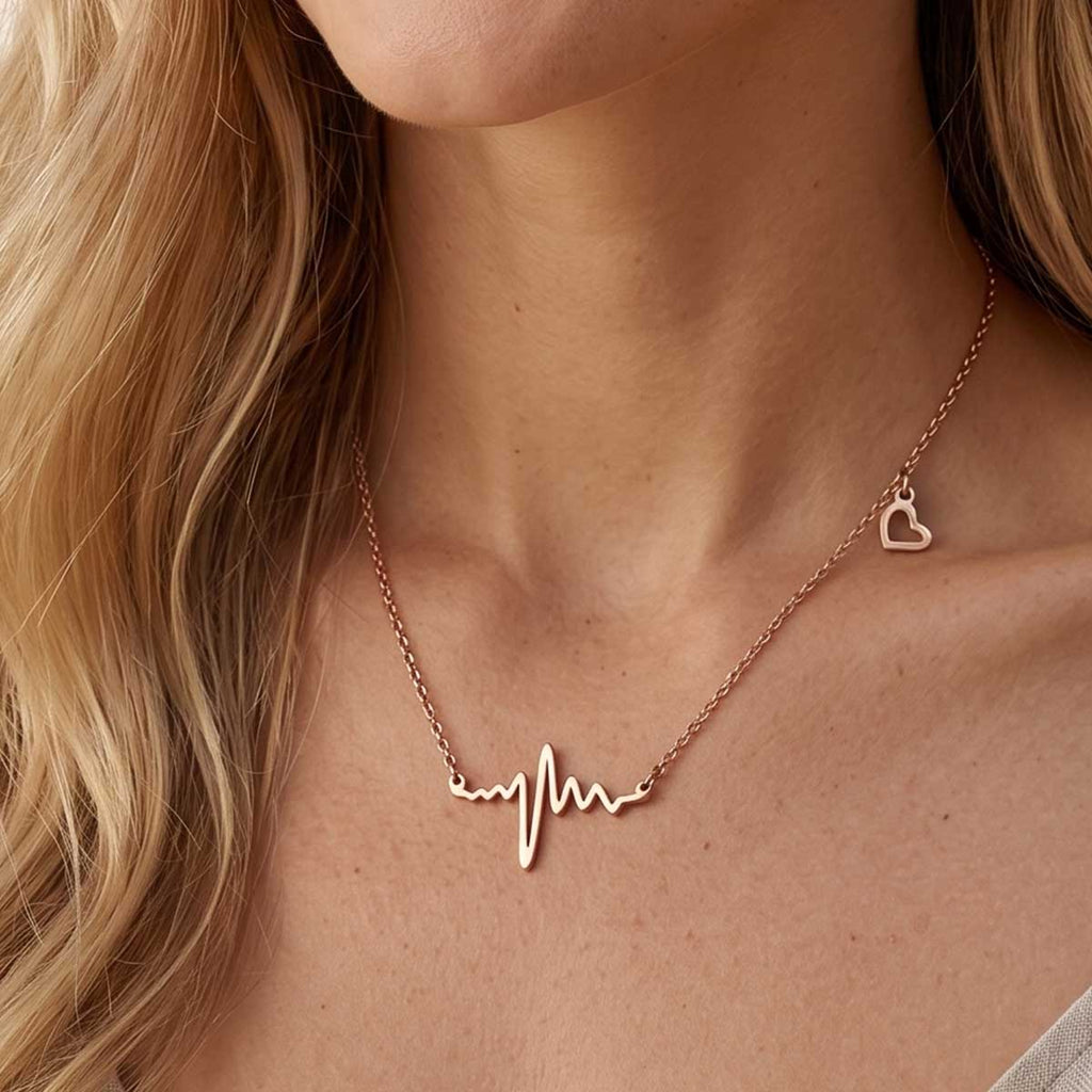 Rosegoldfarbene Damen Halskette mit Herzschlag Anhänger am Hals eines Models getragen.