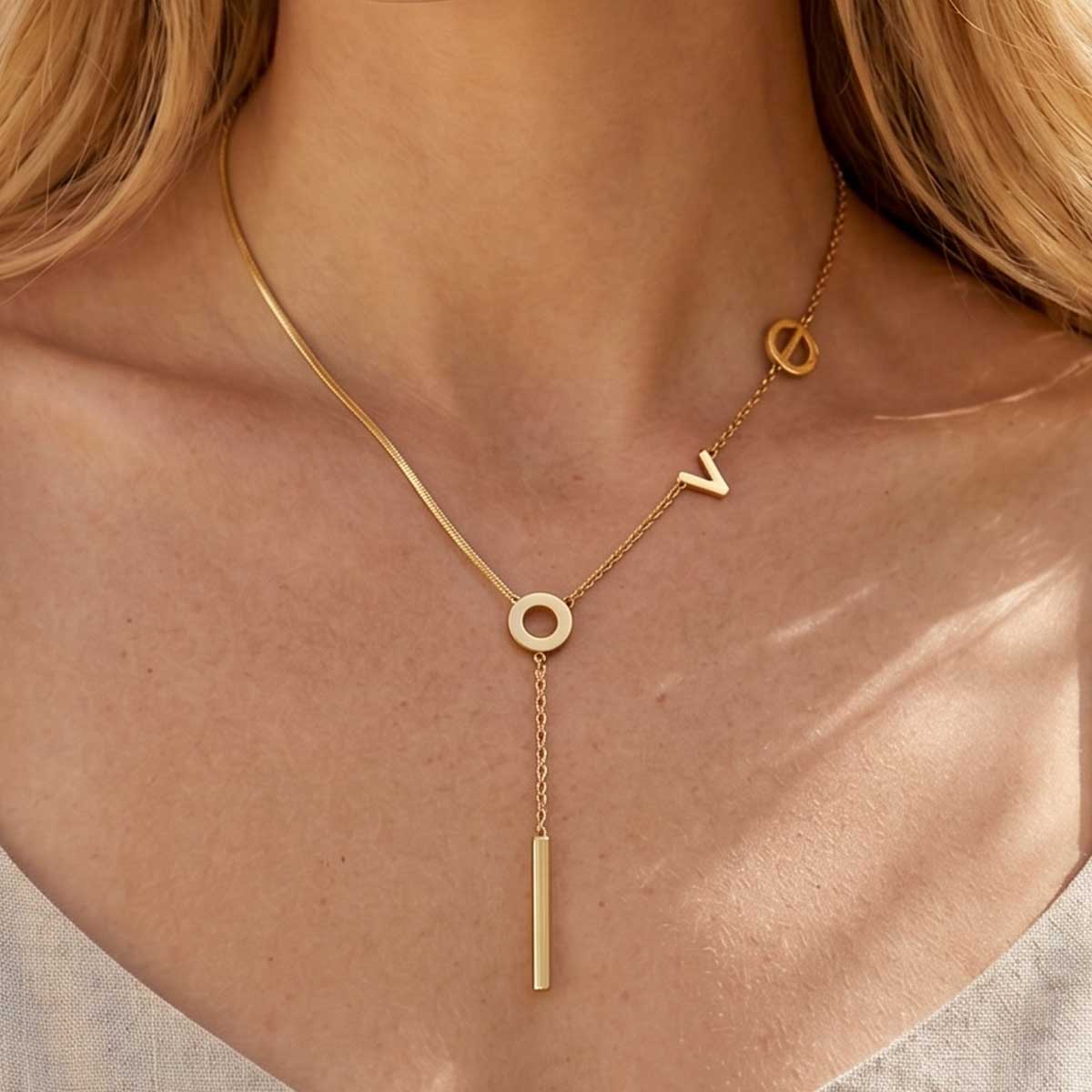 Goldfarbene Damen Halskette mit Love Statement Anhänger am Hals eines Models getragen.