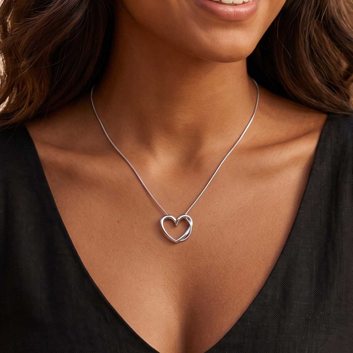 Silberfarbene Damen Halskette mit Herz Anhänger am Hals eines Models getragen.