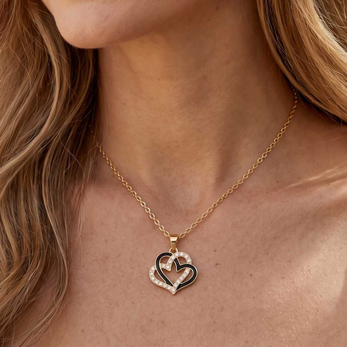 Goldfarbene Damen Halskette mit Doppelherz Anhänger am Hals eines Models getragen.