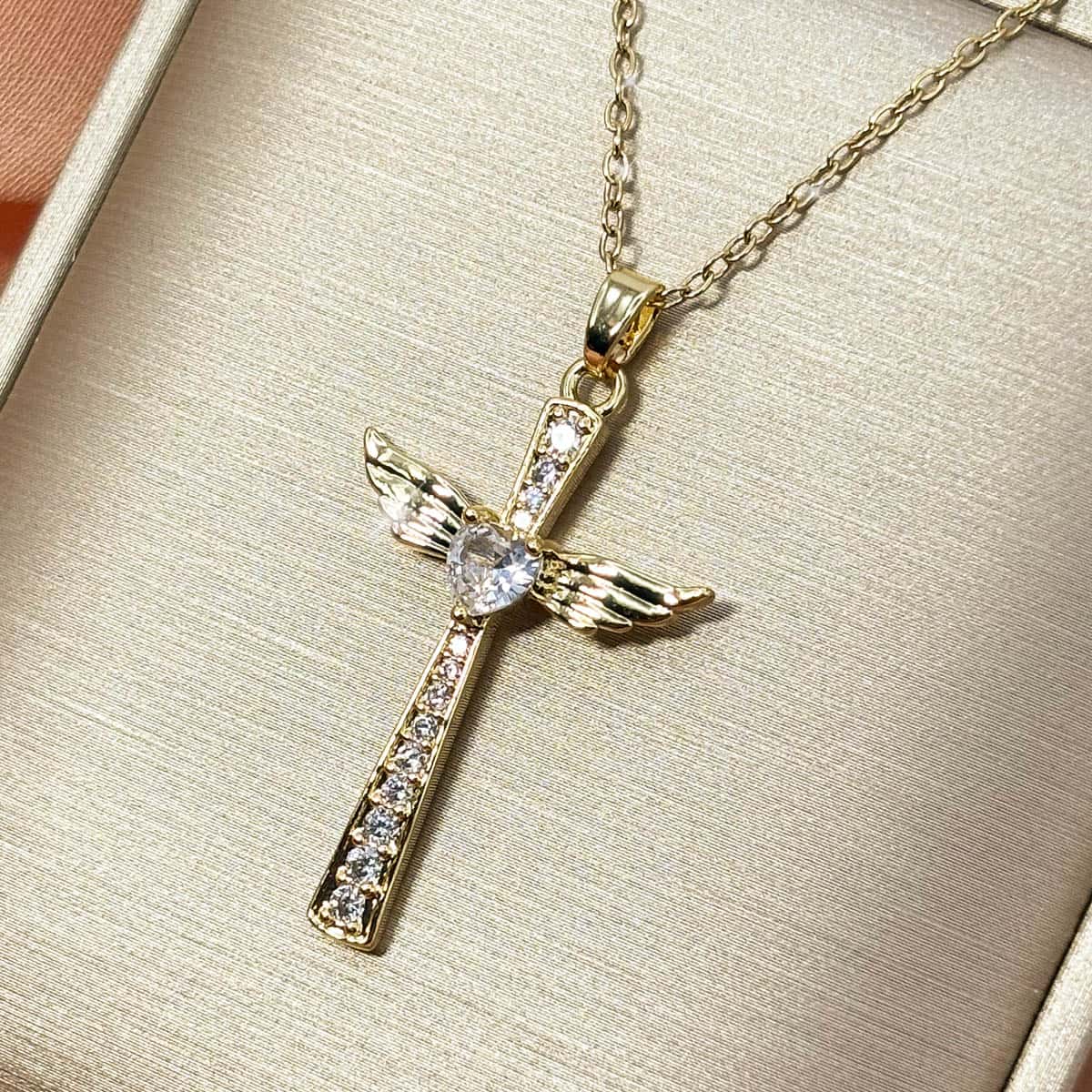 Damen Halskette mit einem eleganten Kreuz-Anhänger, besetzt mit Zirkonia-Steinen, seitlichen Engelsflügeln und einem zentralen Zirkonia-Herz, Nahaufnahme von rechts.