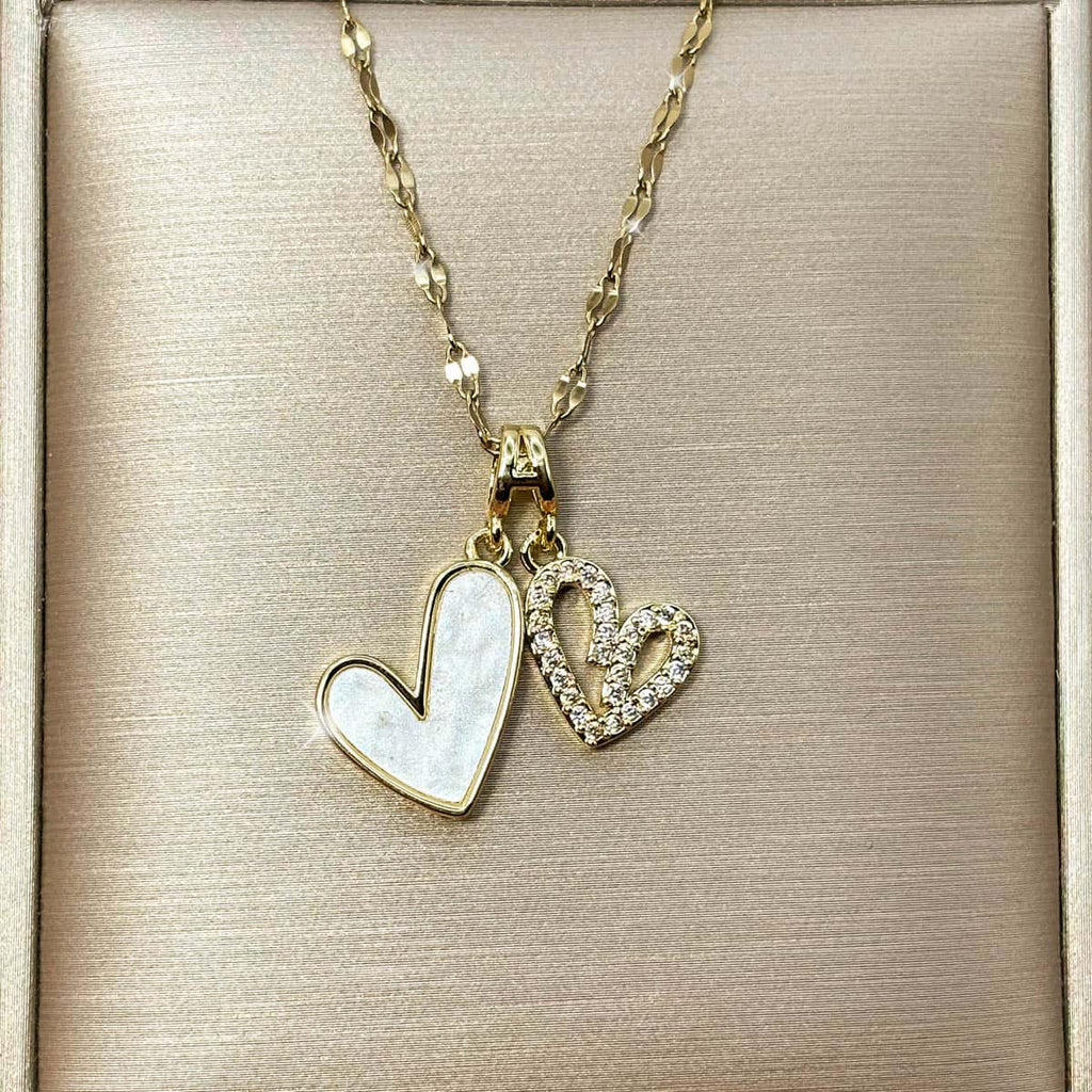 Damen Halskette mit zwei Herz-Anhängern, ein Herz in edler Perlmutt-Optik und ein Herz im Cut-Out-Design mit glitzerndem Zirkonia Besatz, Nahaufnahme der Vorderseite.